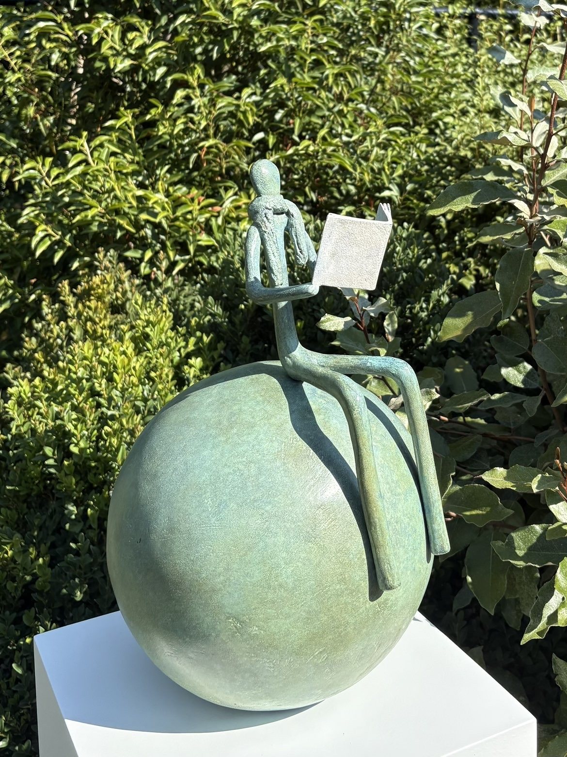 Bronze patiné vert : personnage lisant, assis sur une sphère