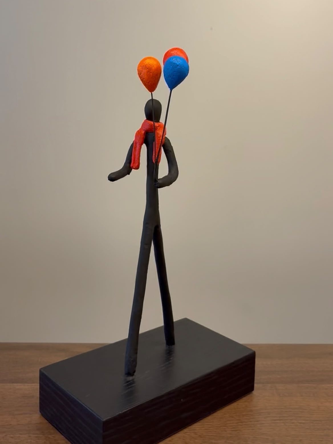 Personnage à l’écharpe rouge tenant deux ballons